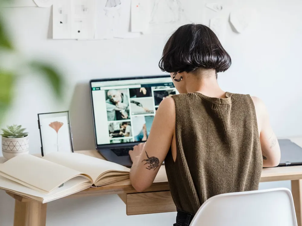 A designer working at a studio desk with framed prints on the wall