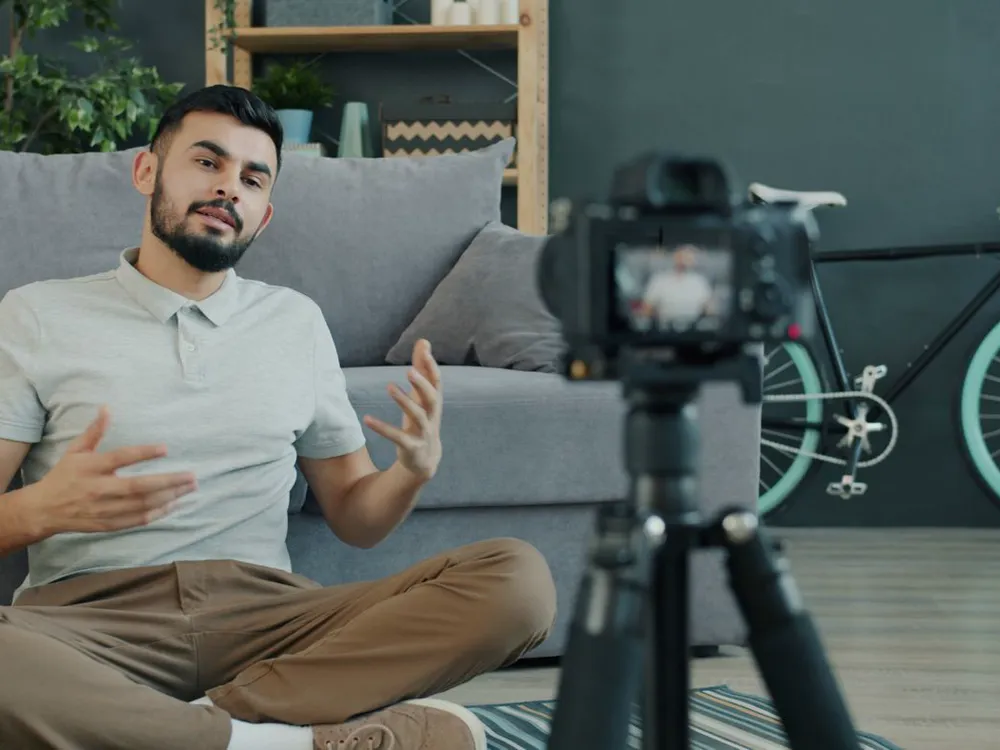 A creator recording a vlog with a camera on a tripod in a bright living room